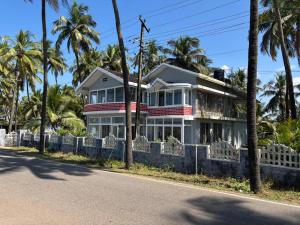 a house on the side of a road with palm trees at Gintara Beach Homestay by evaddo in Kalyānpur