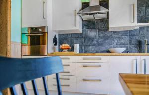a kitchen with white cabinets and a blue chair at Amazing Home In Bjärtrå With Sauna in Bjärtrå