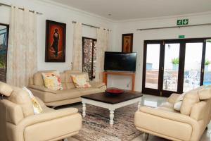 a living room with couches and a flat screen tv at Miyanwe in Pretoria +12 photos