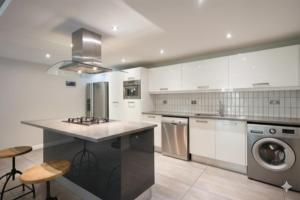 una cocina con gabinetes blancos y una lavadora y secadora en Msotra Party House, en Soweto