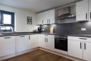 a kitchen with white cabinets and black appliances at Heimbi-Home No 3 I 4-6 Personen I EuropaPark I Family I Garten I Parkplatz I E-Ladestation in Kappel-Grafenhausen