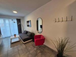 a living room with a red chair and a mirror at Mieszkanie z tarasem - Rybacka in Władysławowo