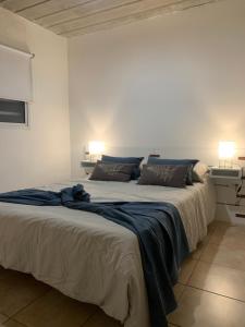 Cama grande en habitación blanca con 2 lámparas en Casa Monte hermoso a media cuadra Del Mar, en Monte Hermoso