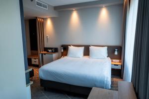 a bedroom with a bed with white sheets and pillows at Holiday Inn - Eindhoven Airport by IHG in Eindhoven