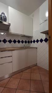 a kitchen with white cabinets and blue and white tiles at Alida in Salò +1 photo