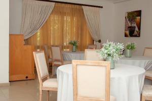 a dining room with white tables and chairs and flowers at Miyanwe in Pretoria