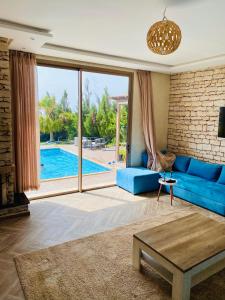 a living room with a blue couch and a pool at Villa Sunset Moulay in Beni Balla