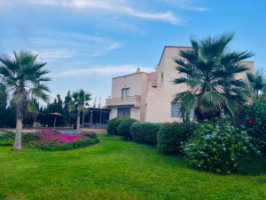 a house with palm trees and flowers in a yard at Villa Sunset Moulay in Beni Balla