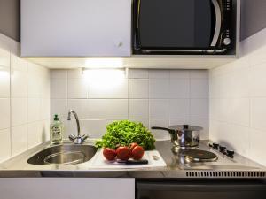 a kitchen counter with a sink and vegetables on a cutting board at Aparthotel Adagio Access Paris Maisons-Alfort in Maisons-Alfort +22 photos