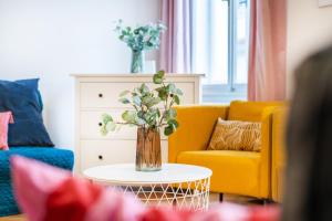 a living room with a yellow couch and a vase of flowers at 2BDR Old Town Square Apartments w Fast Wi-Fi in Prague