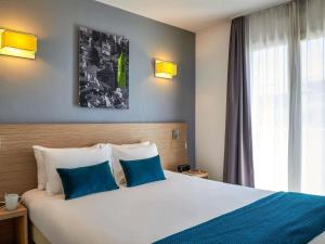 a hotel room with a large bed with blue pillows at Aparthotel Adagio Access Nice Magnan in Nice