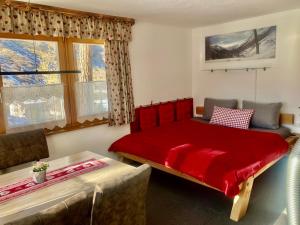 a bedroom with a red bed and a couch at Apartment Gletscherbergblick in Obergurgl