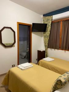 Una habitación de hotel con dos camas y un espejo. en Agriturismo Cavendo Tutus, en Roma