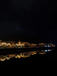a city lit up at night with a body of water at 铂曼智慧酒店-Near the east gate of the Forest Park, about a 10-minute walk-There is a beautiful small river at the entrance-offers free self-service laundry -Attraction Tickets Serivce in advance-Free one-way shuttle service for 4 nights or more in Zhangjiajie