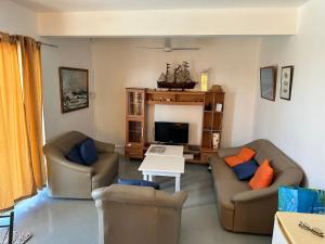 ein Wohnzimmer mit zwei Sofas und einem Fernseher in der Unterkunft Apartment in Montagne Charlot with stunning view of the lagoon in Saint Gabriel