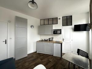 een keuken met witte kasten en een tafel en een eetkamer bij Marc 3 in Saint-Valéry-en-Caux