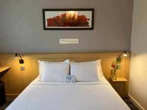a bed with white pillows and a picture on the wall at Kyriad Rennes Sud - Cesson Chantepie in Chantepie