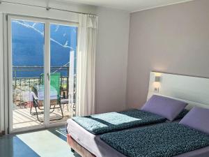 a bedroom with a bed and a balcony with a view at Apartment Bellavista by Interhome in Porlezza