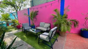 a patio with chairs and a table and a pink wall at Hotel Tropical in Villahermosa +2 photos