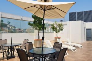 a patio with tables and chairs and an umbrella at EcuOlimpo Lighthouse Stay double in Guayaquil