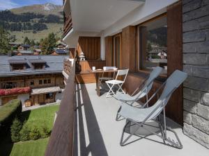 a patio with two chairs and a table on a balcony at Apartment Val Neige 11 by Interhome in Verbier