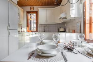 a white kitchen with a table with plates and glasses at Koda Halo Lodge - Sauna, Parking & Playstation in Rovaniemi +23 photos