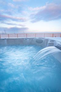 a hot tub with blue water in a swimming pool at Phil Good 1219: Luxurious River View in Charlevoix in Petite-Rivière-Saint-François