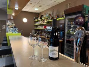 a bottle of wine sitting on a bar with two glasses at Kyriad Rennes Sud - Cesson Chantepie in Chantepie