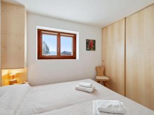 a bedroom with a white bed and a window at Apartment Les Aiguilles Vertes Rez inférieur by Interhome in Crans-Montana