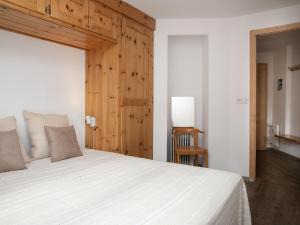 a bedroom with a white bed and a wooden wall at Apartment Galaxie 110 by Interhome in Verbier