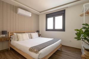 マラガにあるBe Mate Málaga Playaの白いシーツと窓のあるベッドのある寝室