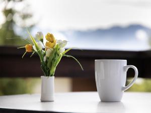 two white vases with flowers and a cup on a table at Apartment Galaxie 217 by Interhome in Verbier