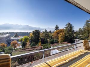 a yellow bench on a balcony with mountains in the background at Studio Jeanne D'Arc Apt- A-8 by Interhome in Crans-Montana