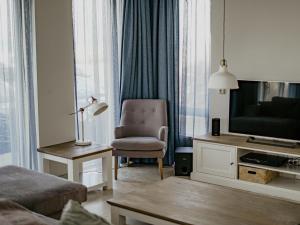 a living room with a chair and a television at Apartment De Zeeparel by Interhome in Egmond aan Zee +24 photos