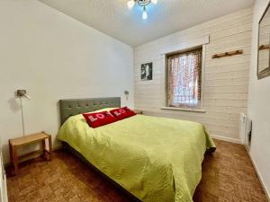 ein Schlafzimmer mit einem grünen Bett mit roten Kissen darauf in der Unterkunft Charmant T2 avec coin montagne, 6 couchages, Monêtier les Bains, proche commerces et navettes ski - FR-1-330F-35 in Le Monêtier-les-Bains