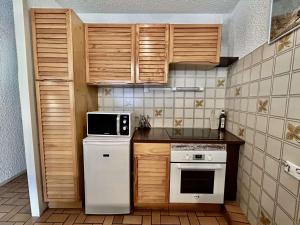 eine Küche mit weißen Geräten und Holzschränken in der Unterkunft Charmant T2 avec coin montagne, 6 couchages, Monêtier les Bains, proche commerces et navettes ski - FR-1-330F-35 in Le Monêtier-les-Bains