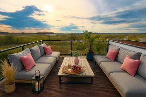 a balcony with couches and a table on a deck at Premium-Strand Chalet an der Nordsee - Noordzee - Zeeland in Breskens