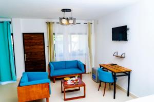 a living room with two blue chairs and a table at Villa Bako Hôtel in Nosy Be