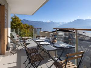 a table and chairs on a balcony with a view of mountains at Apartment Clair-Azur A 41 by Interhome in Crans-Montana
