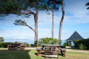 twee picknicktafels in een park met uitzicht op de oceaan bij The Bunker Self Catering in Nairn