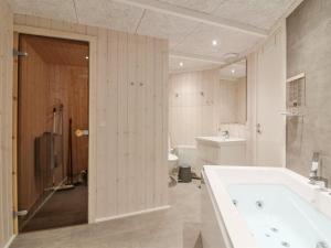 a bathroom with a tub and a toilet and a sink at Holiday Home Franke - 1-1km from the sea by Interhome in Hjørring