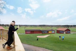 Um homem está em um deck olhando para um campo de golfe. em Skerike Golfhus em Västerås