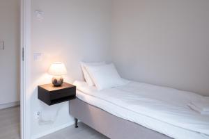 um quarto com uma cama com um candeeiro numa mesa de cabeceira em Skerike Golfhus em Västerås