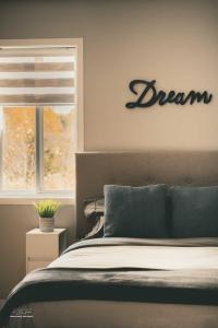 a bedroom with a bed with a dream sign on the wall at Auberge Le Chic in Maniwaki