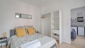 una camera da letto bianca con un letto con cuscini gialli di Flower's Power a Vitry-sur-Seine