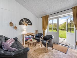 a living room with a black leather couch and chairs at Holiday Home Veijo - 400m to the fjord by Interhome in Spottrup