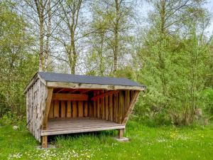 a wooden shelter in a field of grass with trees at Holiday Home Veijo - 400m to the fjord by Interhome in Spottrup