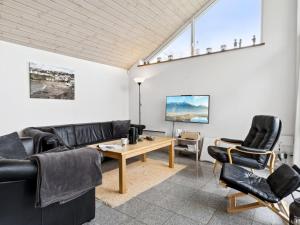 a living room with black leather furniture and a table at Holiday Home Thrugels - 600m from the sea by Interhome in Hadsund