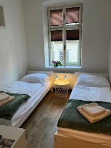 two beds in a room with a window at Apartmán Husova in Prachatice
