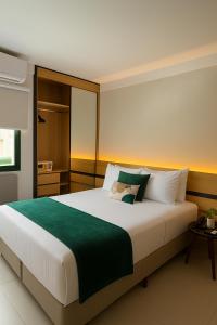 ein Schlafzimmer mit einem großen Bett mit grünen und weißen Kissen in der Unterkunft Flat ESPETACULAR PRAIA DE CAMBURI Long Stay in Vitória